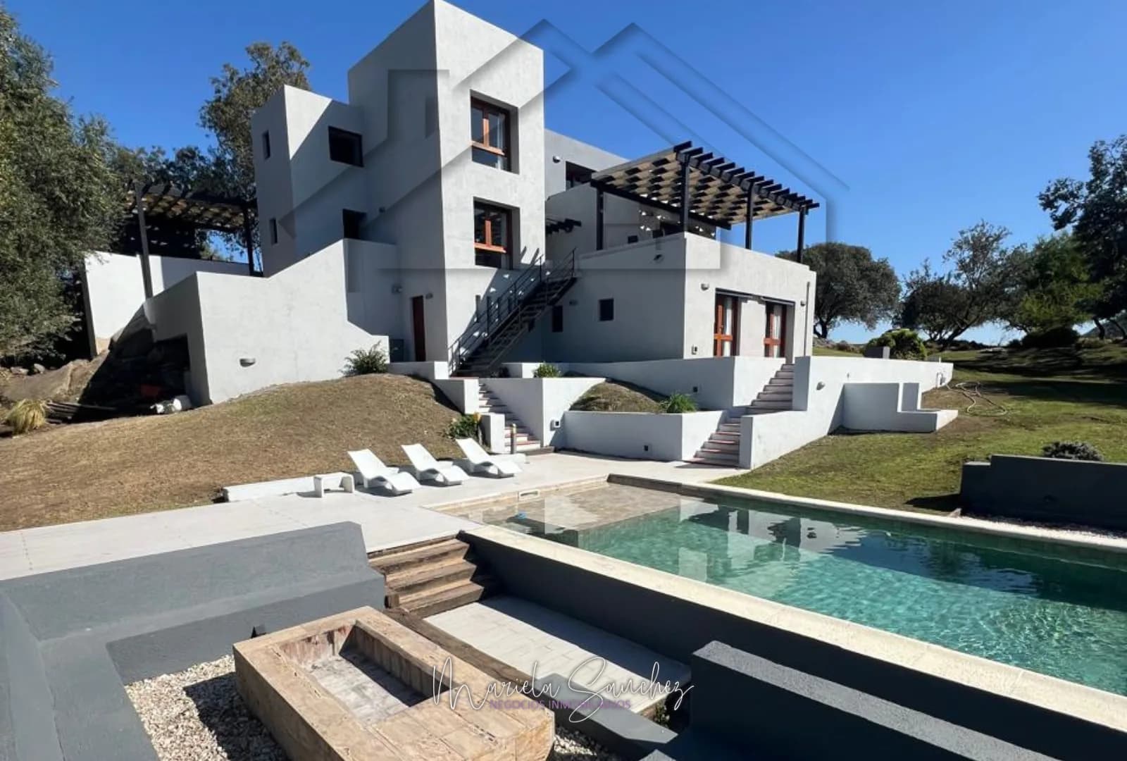La casa en varios niveles vista desde la pileta, con reposeras y fogón